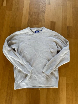 Ljusgrå stickad tröja Jack & Jones - Ljusgrå stickad tröja från Jack & Jones med rund halsringning och långa ärmar. Tröjan har en enkel och stilren design, perfekt för lager på lager och vardagsstil. Materialet ser mjukt och bekvämt ut.