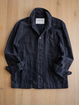 These Glory Days Svart overshirt med knappar - Stilren svart overshirt med klassisk krage och tre framfickor. Använd mycket med cool patina, men mycket kvar att ge! Jackan har knäppning framtill med stora knappar och är tillverkad i ett kraftigare bomullstyg. Perfekt för lager-på-lager och enkel att matcha till olika outfits.