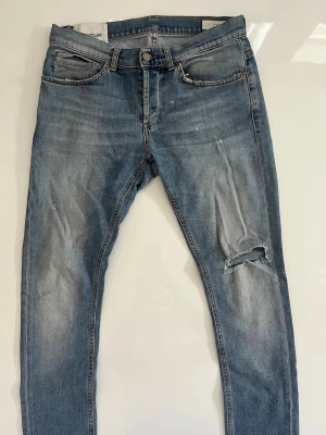 Dondup jeans  - Snygga blå George skinny jeans med slitningar och hål på ena knät. Jeansen har klassisk femficksdesign, dragkedjegylf och är tillverkade i denim med lätt stretch. Perfekta för en avslappnad och trendig look.