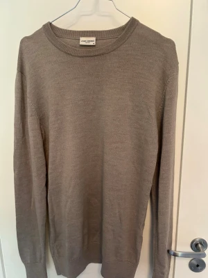 Beige rundhalsad tröja John Henric - Stilren beige tröja från John Henric med rund halsringning och långa ärmar. Tillverkad i ett tunt, mjukt material som passar perfekt för lager på lager. Ribbstickade muddar vid ärmslut och nederkant ger en klassisk look. Nypris 1000 kr