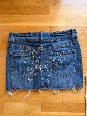 Jeanskjol med paljetter och fransig kant - Lågmidjad jeanskjol med fjärilsmönster i paljett där bak💕några paljetter är borta men det tycker jag att man knappt märker!!