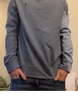 Ljusblå sweatshirt polo Ralph Lauren - En stilren ljusblå sweatshirt med rund hals och långa ärmar. Tröjan har en liten diskret logga på bröstet och ribbade muddar vid ärmslut och nederkant. Perfekt för en avslappnad look och enkel att matcha med jeans.