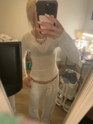 Vit långärmad tight topp - Säljer en vit långärmad topp i tight passform. Toppen är tunn och något genomskinlig, vilket ger en trendig look. Perfekt att styla med olika accessoarer och smycken för en personlig touch.