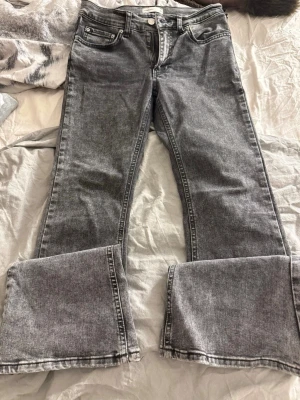 Gråa utsvängda jeans från Perfect Jeans - Säljer ett par gråa utsvängda jeans från Perfect Jeans i storlek 36. Jeansen har bra midja, klassisk femficksmodell och dragkedja med knapp. Materialet är denim med en tvättad look och breda ben. Perfekta för en avslappnad och trendig stil.