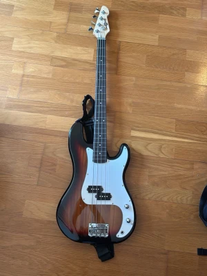 Brun sunburst P-bas  - Säljer en elbas med solbrun burst-finish och vitt plektrumskydd. Det är en fyrsträngad percission bas. Baksidan är svart och det finns en axelrem monterad. Den kommer också med gigbag. 21 band. Liten skada vid e-strängens stämskruv. Det kommer inte gå att maila, så antigen upphämtning eller mötesplats nära Skåne.