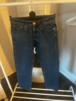 J&J jeans - Klassiska mörkblå jeans med rak passform och fem fickor. Jeansen har gylf med knappar samt detaljer i guldmetall. Tillverkade i denim, perfekt för en avslappnad och stilren look. W29 L32. Hör av er vid frågor! Använt max 5 ggr!