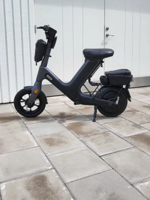 Svart elcykel med modern design - Säljer en svart elcykel med minimalistisk och modern ram. Cykeln har en bekväm sadel, små hjul och batteri placerat under sadeln. Perfekt för smidig transport i stan och enkel att parkera tack vare stödet. Nåt är fel på den, verkstan sa att det skulle kosta ca 1500 att laga