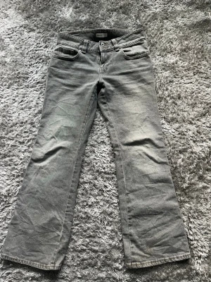 Grå bootcut jeans  - Ett par jättefina bootcut jeans från Gina tricot. Jeansen har klassiska fem fickor, bälteshällor och knappgylf. Materialet är denim i bomull och passformen är rak med lätt utsvängda ben.