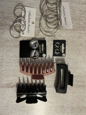 Set med hårklämmor och örhängen - Säljer ett mixat set med tre hårklämmor i svart, beige och matt svart samt örhängen i silverfärg, inklusive stora ringar, hjärtformade clips och små hoops med stjärnor. Perfekt för att variera din look och matcha olika outfits.