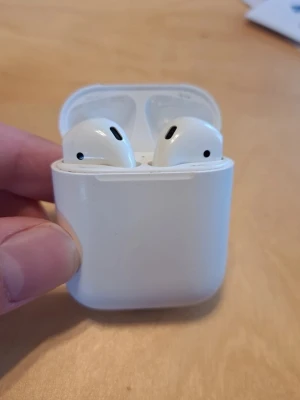 AirPods Trådlösa vita hörlurar med laddningsetui - Säljer ett par trådlösa vita hörlurar med tillhörande laddningsetui. Hörlurarna har stilren design och passar perfekt för musik, poddar och samtal. De är små, smidiga och enkla att ta med sig överallt. Laddningsetuiet är också vitt och kompakt.