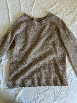 Beige stickad tröja från Vero Moda - Mysig beige stickad tröja från Vero Moda med rund halsringning och ribbade muddar vid ärmslut och nederkant. Perfekt för lager på lager och enkel att matcha med jeans eller kjol. Materialet känns mjukt och bekvämt.