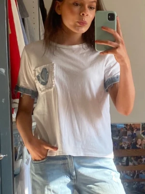 Vit tshirt med jeansdetaljer - Vit tshirt med jeansdetaljer!! Säljs för 100kr! Strl S. Jeansdetaljerna är påsydda men T-shirten är ursprungligen från zara. Jeansdetaljerna binder verkligen ihop en jeansoutfit✨✨