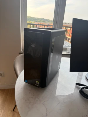 Acer Predator Orion 3000 - Säljer en svart stationär gamingdator med Predator-logga på fronten. Chassit är stilrent och har en blank framsida med diskreta detaljer. Datorn har RTX och Intel-klistermärken på fronten. Perfekt för gaming och tunga program. 4060 RTX