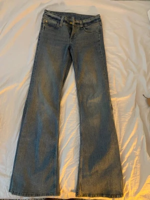 Cheap monaday jeans - Helt nya Cheap monday jeans i blå bootcut med utsvängda ben och fem fickor. Jeansen är låg midjade och stängs med dragkedja och knapp. Tillverkade i denim med en lätt tvättad look, perfekta för en avslappnad stil.