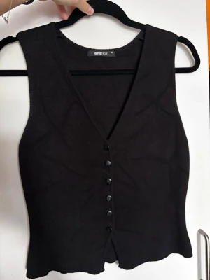 Svart stickad väst från Gina Tricot - Svart stickad väst med v-ringning och knappar framtill från Gina Tricot. Modellen är figurnära och har en klassisk, stilren look som passar till många outfits. Skitsnygg men har inte kommit till användning, kändes lite för stor på mig i efterhand tyvärr! Den har legat lite vikt i garderoben så har lite veck av det men det försvinner i tvätt/steamning/strykning:)