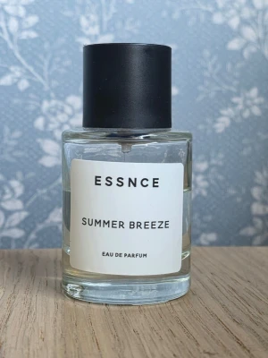 ESSNCE Summer Breeze parfym - Fräsch parfym från ESSNCE med namnet Summer Breeze. Flaskan är cylindrisk i genomskinligt glas med svart matt kork och enkel vit etikett. Doften är en Eau de Parfum.  Flaskan har förvarats mörkt och svalt. 50 ml från början. Se bild för mängd som är kvar. 