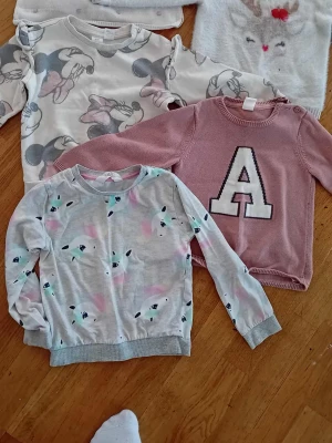 Grå sweatshirt med pastellmönster - En grå sweatshirt med pastellfärgade mönster och små ansikten, rund hals och ribbade muddar. Perfekt för dig som gillar en lekfull och avslappnad stil.