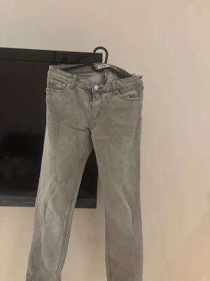 Grå jeans från Pull&Bear - Säljer ett par grå jeans från Pull&Bear med klassisk femficksmodell och raka ben. Jeansen har bälteshällor, knappgylf och är tillverkade i ett mjukt denimtyg. Perfekta för en avslappnad och trendig look.