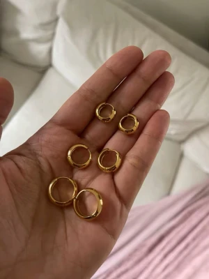 3 par Guldpläterade hoops örhängen 12,10,8 mm stora - 18k guldpläterad, vattentåliga, går att duscha med de. Rostfritt stål. Säljer ett set med sex guldpläterade hoops örhängen i olika storlekar. De är klassiskt runda och har en blank finish som ger en snygg och stilren look. Perfekta att mixa och matcha för en personlig touch. Materialet är metall med guldplätering.