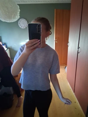 Ljusblå stickad kortärmad tröja💕 - Säljer en ljusblå stickad tröja med korta ärmar och rund hals. Tröjan är croppad och har ribbstickade detaljer vid halsen, ärmslut och nederkant. Perfekt för att matcha med höga jeans eller kjol.💕