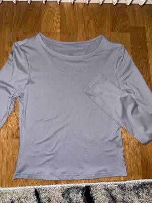 Ljusgrå långärmad topp - En stilren ljusgrå långärmad topp med rund halsringning. Tillverkad i mjukt material som känns skönt mot huden. Perfekt att matcha med jeans eller kjol för en enkel och clean look.