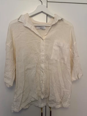 Vit skjorta från Primark i linne - Säljer en vit skjorta från Primark i storlek L. Skjortan är tillverkad i linne, har knappar framtill och en bröstficka. Den har en avslappnad passform och trekvartsärmar, perfekt för dig som gillar en enkel och luftig stil.