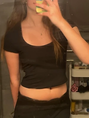 Svart croppad topp med kort ärm - En enkel och stilren svart croppad topp med korta ärmar och rundad, djup urringning. Tillverkad i mjukt bomullsmaterial för en bekväm känsla.