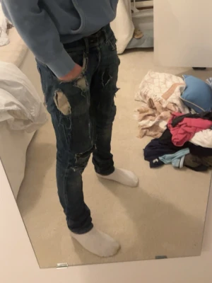 Dondup jeans - Säljer ett par mörkblå jeans med skinny fit och flera slitningar och hål på benen. Jeansen har klassisk femficksdesign och är tillverkade i denim med stretch. Perfekta för en avslappnad och trendig look. Jeansen är i rätt kasst skick därav priset med b.la ett osynligt hål i skrevet.
