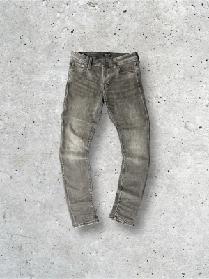 Grå Jack&Jones jeans - Snygga grå slim fit jeans med klassisk femficksmodell. Jeansen är perfekta för skolan eller vid speciella tillfällen. Storlek W31L34 Kontakta vid intresse👊Kan släppa riktigt billigt och det är redan billigt