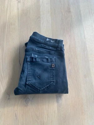 Dondup Jeans - Snygga svarta jeans från Dondup med klassisk femficksdesign och en slim passform. Jeansen har en diskret tvättad look och snygga slitningar. Perfekta för en stilren och modern look.