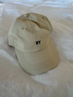 Beige keps med NY-brodyr - Skitnygg stilren keps perfekt för våren och sommarn! Aldrig använd! 