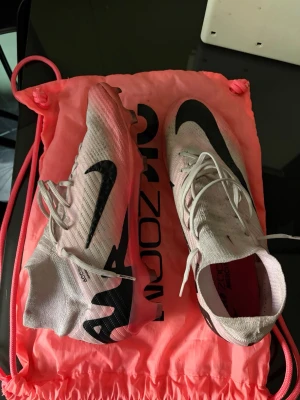 Nike Mercurial Zoom rosa fotbollsskor - Varför jag säljer dessa skor är för att en av dobbarna har gått av (båda skorna) men det är riktigt bra skick. Skadan finns på sista bilden. De är i jättebra skick annars och har endast använt de fåtal gånger. Kartong o allt ingår.