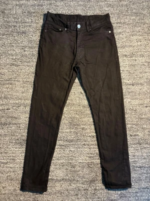 Svarta slim jeans från Denim - Säljer ett par svarta slim fit jeans från Denim i storlek 30/32. Klassisk femficksmodell med knapp och dragkedja framtill. Jeansen har en smal passform och är tillverkade i ett mjukt denimtyg som sitter snyggt på benen.
