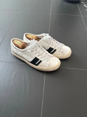 Vita Golden Goose sneakers med svart detalj - Stilrena vita sneakers från Golden Goose med svart rand på sidan och klassisk låg siluett. Skorna har vita snören, beige sula och är tillverkade i läder. Storlek 42 men passar 43 också