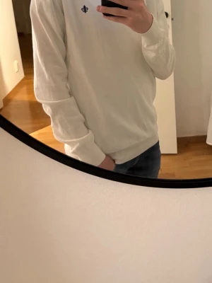 Vit tröja från Morris Stockholm XS - Säljer en stilren vit tröja från Morris Stockholm i storlek XS. Tröjan har rund halsringning, långa ärmar och en liten broderad logga framtill. Perfekt för en clean och klassisk look.