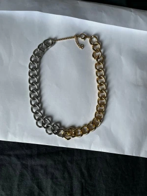 Chunky halsband i guld och silver - Snyggt chunky halsband med stora länkar i både guld- och silverfärg. Halsbandet har en justerbar kedja och är tillverkat i metall. Perfekt statement-piece för att lyfta din outfit.