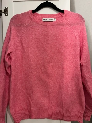 Rosa stickad tröja från ONLY - Mysig rosa stickad tröja från ONLY med rund halsringning och långa ärmar. Tröjan har ribbade muddar vid ärmslut och nederkant, perfekt för att hålla värmen. Enkel och stilren design som passar till det mesta. ⭐️Har endast använt tröjan 1-2 ggr så den är i väldigt bra skick, på bilden var den dock lite skrynklig men annars jättefin💕