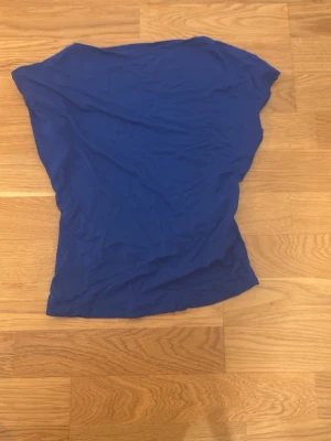 Blå ärmlös topp med öppen rygg - En enkel blå topp med ärmlös design och rund halsringning. Tunt och mjukt material som känns skönt mot huden. Perfekt att matcha med jeans eller kjol för en avslappnad look.