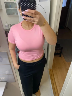 Rosa croppad t-shirt - Snygg rosa croppad t-shirt med rund halsringning och korta ärmar. Perfekt för dig som gillar en enkel men trendig stil. Materialet är mjukt och stretchigt, vilket gör toppen bekväm att bära hela dagen. Aldrig använd men har ej prislappen kvar 
