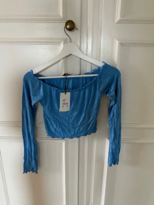 Croppad off shoulder topp - Blå croppad off shoulder topp från Bikbok, storlek XS. Oanvänd! 