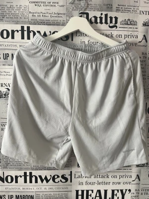 Ljusgrå sportiga shorts med resår - Snygga ljusgrå shorts med elastisk midja och avslappnad passform. Perfekta för träning eller chill dagar. Tillverkade i ett lätt och ventilerande syntetmaterial som håller dig sval. Enkla att matcha med t-shirt eller hoodie. Se måttet på bilderna. 