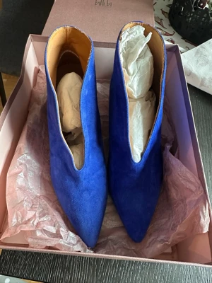 Koboltblåa stövletter från Billi Bi - Säljer ett par koboltblåa stövletter från Billi Bi i mjuk mocka. Skorna har spetsig tå, smal klack och en djup v-ringad öppning framtill. Insidan är fodrad i beige läder för extra komfort. Perfekta för dig som vill sticka ut med färg!