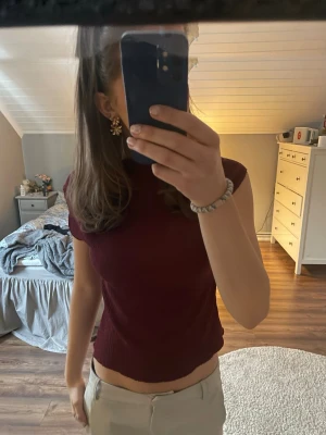 Mörkröd ribbad kortärmad topp - En snygg mörkröd ribbad topp med korta ärmar och croppad passform. Helt oanvänd, står storlek XS men passar större än så också🩷