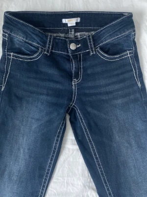 Lowaist jeans - OBS!kontakta mig om ni vill ha bilder på hur dem ser ut på! Säljer ett par mörkblå jeans med kontrastsömmar och snygga broderade bakfickor med paljettdetaljer. Klassisk femficksmodell och ganska lågmidjade💕💕