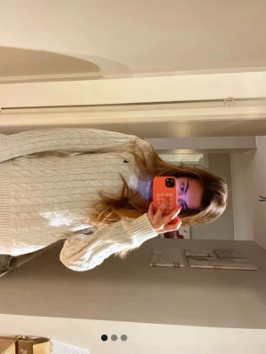 Vit kabelstickad tröja från Gant - Kabelstickad tröja i offwhite från Gant med rund halsringning och diskret logga broderad på bröstet. Tröjan har långa ärmar och ribbade muddar vid ärmslut och nederkant. Perfekt för lager-på-lager och klassisk stil.