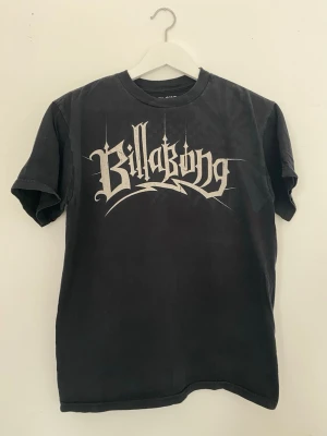 Svart Billabong t-shirt med tryck - Cool svart t-shirt från Billabong med stort grafiskt tryck på bröstet i grått. Tillverkad i mjuk bomullsmix med klassisk passform och rund hals. Perfekt för en avslappnad streetwear-look. 