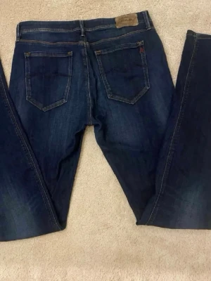 Mörkblå Replay Jeans - Snygga mörkblå Levi's 711 Skinny Jeans med klassisk femficksdesign och guldfärgade nitar. Jeansen har en smal passform och är tillverkade i stretchigt denim för extra komfort. Perfekta för dig som gillar en tidlös och stilren look.