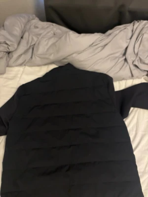 Svart cardigan jacka från Zara - Säljer en svart cardigan jacka från Zara i storlek L. Jackan har en klassisk quiltad design med breda paneler och är tillverkad i ett mjukt, vadderat material som håller dig varm under kalla dagar. Perfekt för dig som vill ha en stilren och enkel vinterjacka. Liten i storleken skulle säga att de är en M