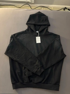 Svart hoodie från Acne Studios - Snygg svart hoodie från Acne Studios med klassisk design och huva. Tröjan har en avslappnad passform och är tillverkad i mjukt material som känns skönt mot huden. Perfekt för en stilren och enkel look.