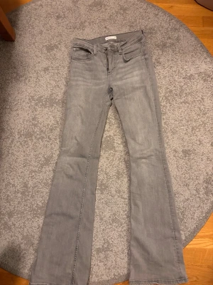 Grå bootcut jeans  - Säljer ett par gråa bootcut jeans från Perfect Jeans. De har klassisk femficksdesign, låg/medelhög midjaoch utsvängda ben. Jeansen är i mjukt denimtyg och har dragkedjegylf med knapp. Perfekta för en trendig och avslappnad stil. Nypris 399